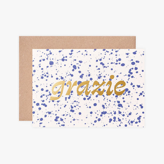 Greeting card with 'grazie' text on a white background with blue dots, brown envelope.